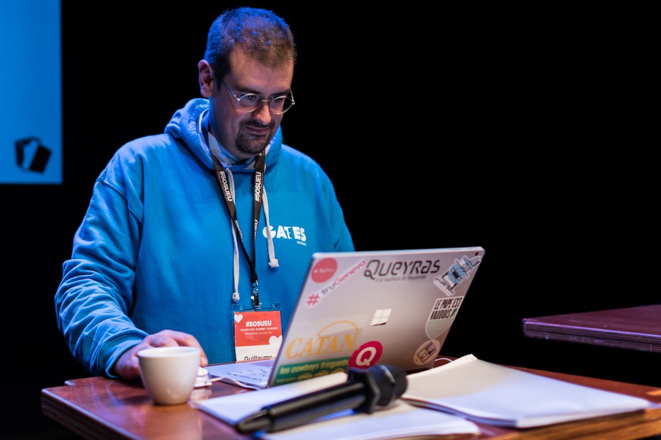 Guillaume Alexandre en conférence avec son laptop (stickers Tru Geneva, Sourcing Summit Europe) et son hoodie Gates Solutions